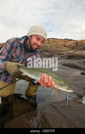 Angler présente le poisson qu'il a pris la mouche dans l'Arctique canadien. Banque D'Images