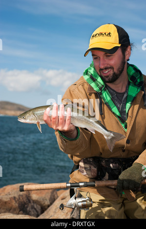 Angler présente le poisson qu'il a pris la mouche dans l'Arctique canadien. Banque D'Images