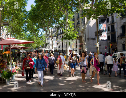 Espagne, Catalogne, Barcelone, les gens à marcher le long de l'arbre central promenade ombragée de La Rambla avenue historique passé étals de fleurs. Banque D'Images