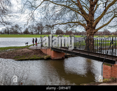 Jeune couple et de chien à pied près de Old Deer Park footbridge après de fortes précipitations hivernales - Richmond upon Thames, Surrey, UK Banque D'Images