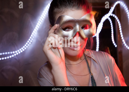 Femme tenant un masque parti en face de face, portrait Banque D'Images