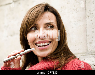 Woman smoking cigarette électronique, smiling Banque D'Images