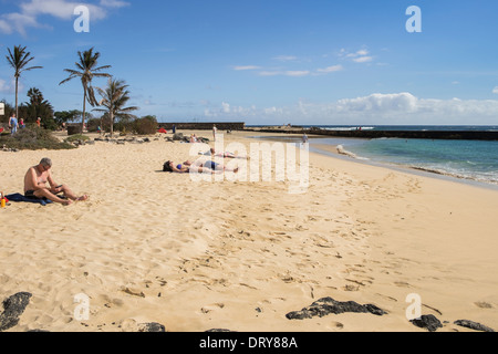 Les gens en train de bronzer sur la plage de sable de Playa de las Cucharas à Costa Teguise, Lanzarote, Canaries, Espagne, Europe. Banque D'Images