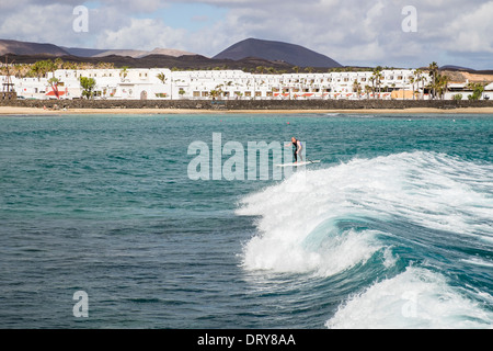 L'homme sur une planche de surf paddleboarding sur de grosses vagues en mer au large de Playa Charcos beach à Costa Teguise, Lanzarote, Îles Canaries Banque D'Images