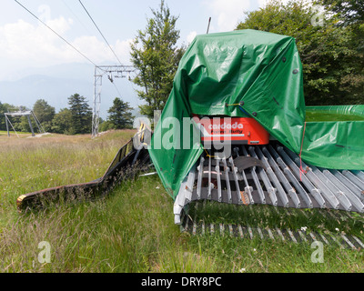 Une chenillette sur une piste de ski, d'herbe verte sur le sommet du Monte Cardada, Suisse, lors d'une chaude journée d'été. Banque D'Images