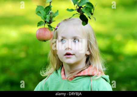 Petite fille regarde pensivement l'apple dans un jardin Banque D'Images