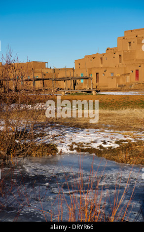 Adobe structure Northside à Taos Pueblo avec ruisseau couvert de glace en premier plan. Banque D'Images