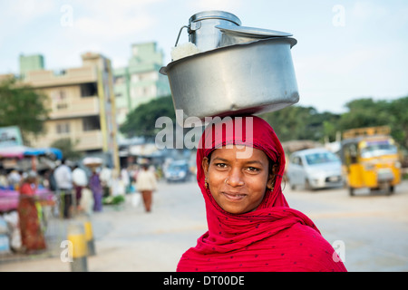 Les Indiens de la caste inférieure pauvre adolescente portant un pot de riz sur la tête. L'Andhra Pradesh, Inde Banque D'Images