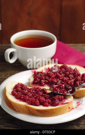 Le pain avec confiture de framboises et une tasse de thé sur la table Banque D'Images