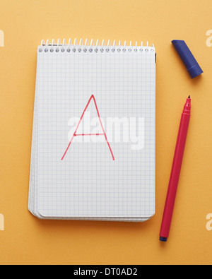 Une lettre en page du bloc-notes manuscrites sur fond jaune alphabet Banque D'Images