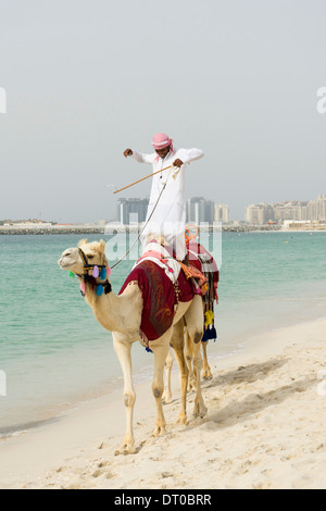 Les touristes de prendre un tour de chameau sur la plage au quartier du port de plaisance de Dubaï en Émirats Arabes Unis Banque D'Images