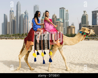 Les touristes de prendre un tour de chameau sur la plage au quartier du port de plaisance de Dubaï en Émirats Arabes Unis Banque D'Images