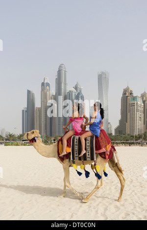 Les touristes de prendre un tour de chameau sur la plage au quartier du port de plaisance de Dubaï en Émirats Arabes Unis Banque D'Images