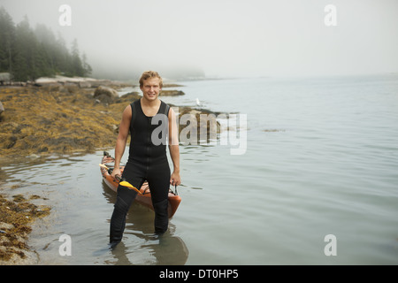 L'état de New York USA man wetsuit kayak sur le rivage en temps brumeux Banque D'Images