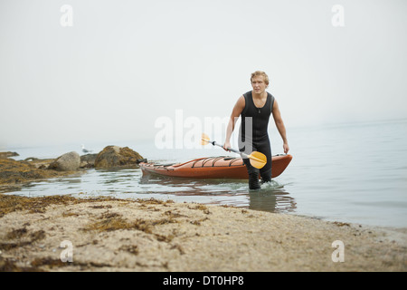 L'état de New York USA man wetsuit kayak sur le rivage en temps brumeux Banque D'Images