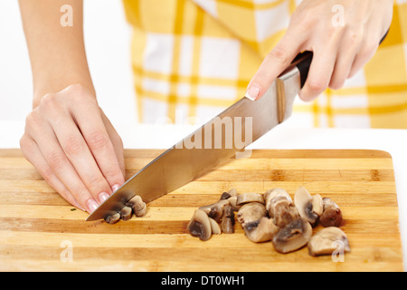 Closeup of woman's hands cook chopping champignon champignons sur une planche en bois isolé sur blanc, selective focus Banque D'Images