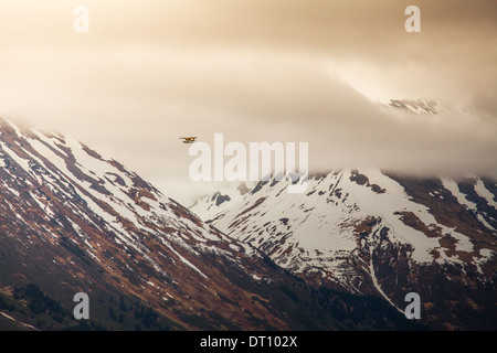 Petit avion voler à travers les montagnes près de Moose Pass Alaska avec des nuages de tempête. Banque D'Images