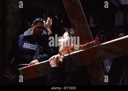 Un chrétien dévot porte une croix en bois reproduisant le Chemin de Croix du Vendredi saint au cours de procession le long de la Via Dolorosa street que l'on croit être le chemin que Jésus a marché sur le chemin de sa crucifixion dans la vieille ville de Jérusalem-Est, Israël Banque D'Images