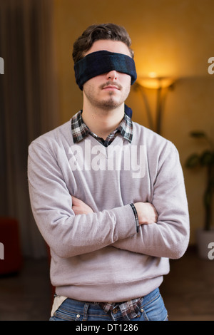 Jeune homme, les yeux bandés, à la maison dans la salle de séjour ne peuvent pas voir Banque D'Images