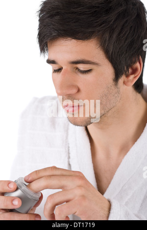 Soins du Visage - Young man applying moisturizer Banque D'Images