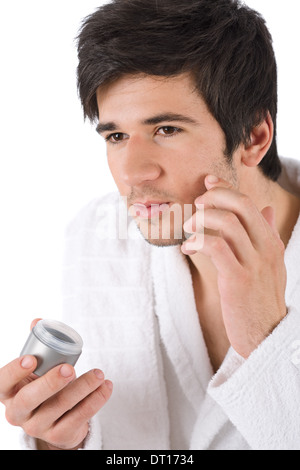 Soins du Visage - Young man applying moisturizer Banque D'Images