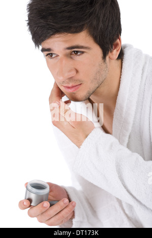Soins du Visage - Young man applying moisturizer Banque D'Images