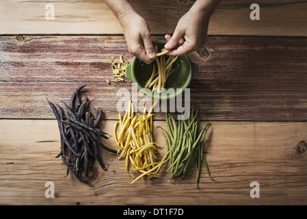 Jaune et Noir vert bio haricots Légumes frais étant en tête et queue par une personne avant de cuisiner et manger Banque D'Images