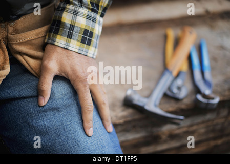 Atelier de bois d'une terre d'une personne à un établi et des outils et pinces pinces alignés sur une planche de bois Banque D'Images