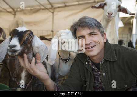 Un homme avec un groupe de chèvres dans un enclos de bétail maintient pour la viande et le lait Banque D'Images