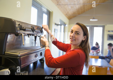 Une jeune femme faire le café à l'aide d'une grosse machine à café Banque D'Images