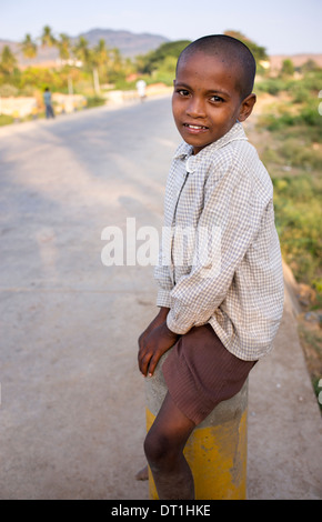 Happy smiling indiens de basse caste garçon assis sur un poteau. L'Andhra Pradesh, Inde Banque D'Images