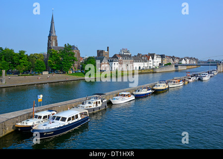 Maastricht River Meuse (maas) et long mur de quai séparant le canal principal de la voie navigable fournit des amarrages pour visiter les bateaux à moteur église de la flèche de l'UE Banque D'Images