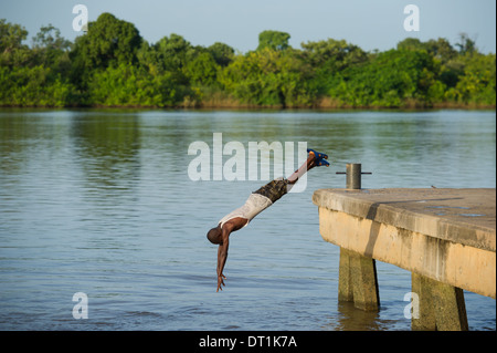 Garçon de plonger dans le fleuve Gambie à partir de la jetée, sur l'île de MacCarthy Janjangbureh, Gambie Banque D'Images