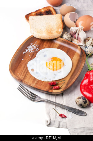 Le petit-déjeuner avec des oeufs au plat sur table en bois servi avec des toasts, Red Hot Chili Peppers et fourche vintage over white Banque D'Images