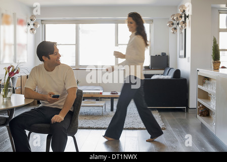 Couple at Home Man using smartphone Woman walking passé Banque D'Images