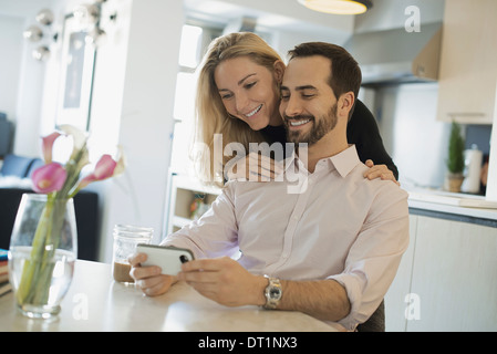 Couple à la maison regarder des images sur smartphone Banque D'Images