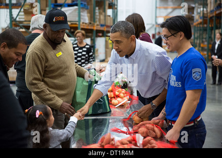 Le président américain Barack Obama serre la main d'une jeune fille alors qu'il, la Première Dame Michelle Obama, et la première famille participer à un projet de service grâce à la banque alimentaire de la région de la capitale le 27 novembre 2013 à Washington, DC. Banque D'Images