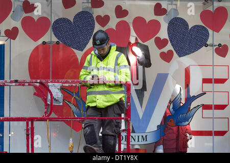 London UK. Le 6 février 204. Un travailleur se tient devant une vitrine décorée avec des cœurs comme boutiques soyez prêt pour la Saint-Valentin qui est associé avec l'amour romantique en décorant avec devantures windows Crédit : coeurs amer ghazzal/Alamy Live News Banque D'Images