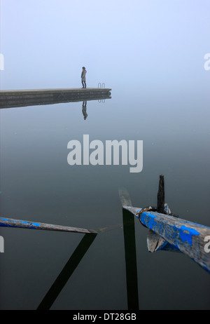 Femme seule sur le quai du petit port de pêche d'Agios Achilleios islet, Mikri Prespa Lake, Florina, Macédoine, Grèce. Banque D'Images