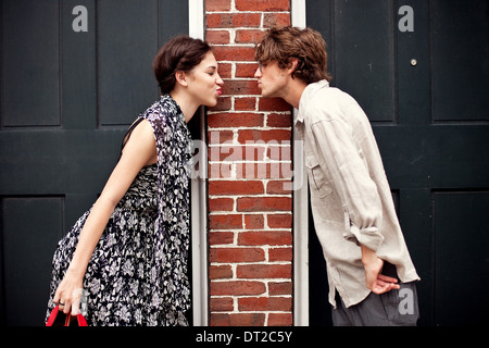 Jeune couple debout devant la porte et mur de brique Banque D'Images