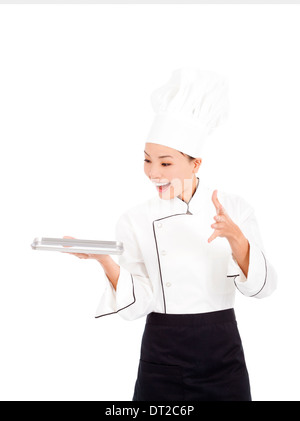 Cook incroyable femme chef holding bac et montrant quelque chose Banque D'Images