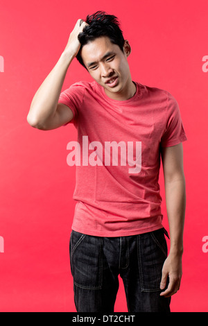 Portrait of Asian man standing à la hâte. Fond rouge. Banque D'Images