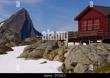 Chalet de montagne sur îles Lofoten en Norvège avec des pics de montagne s'élevant au-dessus de Banque D'Images