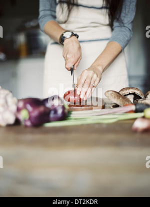 Une cuisine domestique une table top Jeune femme couper des légumes frais avec un couteau Banque D'Images