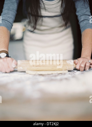 Une cuisine domestique d'une femme préparant un repas rouler une pâte sur un dessus de table Banque D'Images