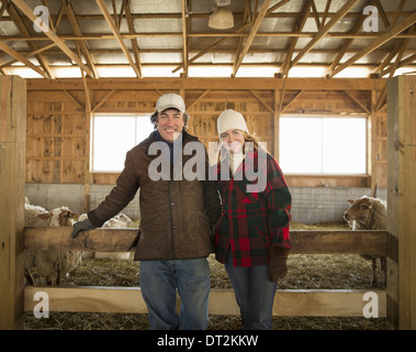 Une ferme biologique en hiver à Cold Spring New York State un agriculteur et une femme debout par une plume pleine de moutons Banque D'Images