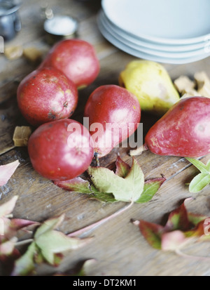 Une table de cuisine intérieure d'un petit groupe de poires biologiques frais et une pile de plaques blanches Banque D'Images