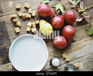 Une table de cuisine intérieure d'un petit groupe de poires biologiques frais et une pile de plaques blanches Banque D'Images