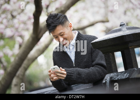 Vue sur cityA jeune homme à l'extérieur dans un parc de la ville assise sur un banc Banque D'Images
