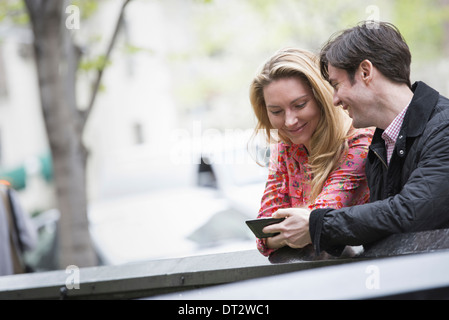 Vue sur cityYoung les gens à l'extérieur dans un parc de la ville deux personnes assises côte à côte en regardant un téléphone intelligent Banque D'Images